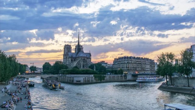Notre Dame cathedral in Paris, France, against sunset sky. Scenic view over la Cite with fast moving dramatic clouds. 4K Day-night transition timelapse.