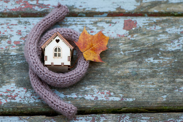  Toy house is wrapped in a warm scarf with an autumn leaf
