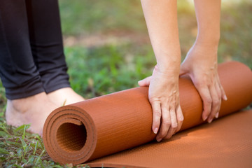 close up of Woman rolling her mat after a yoga class in the park