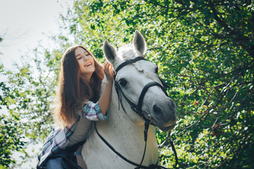 Girl teenager and white horse in a park in a summer
