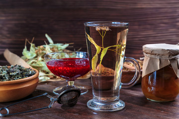 tea from dried lime flowers, raspberry jam is on the dark wooden surface of the table