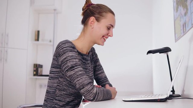 Happy smiling woman with laptop computer having video conference at home or office. She is waving her hand