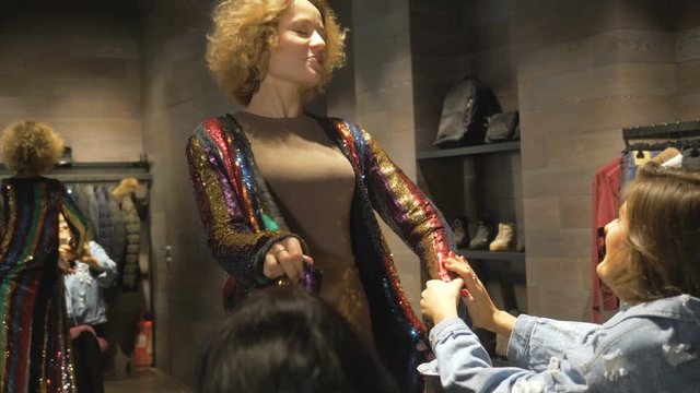 Young girls fool around in the locker room of an expensive store.