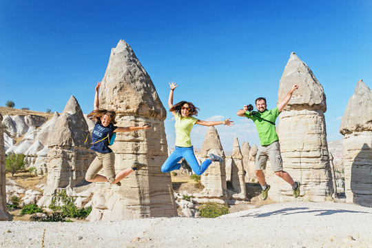 Group of happy caucasian Friends jumping and having fun while travelling among Cappadocia fairy chimneys at summer