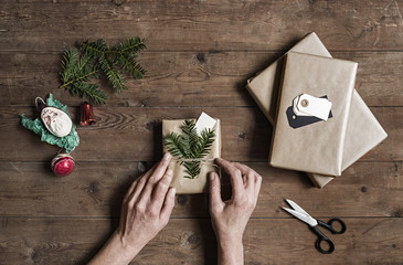 Woman wrapping Christmas presents on wooden table