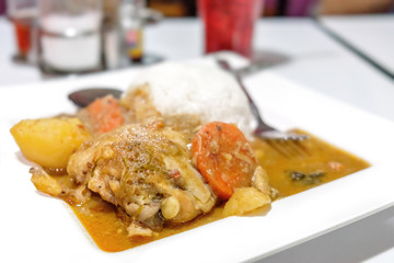 Thai cuisine, chicken curry with rice on the blurred cafe background.