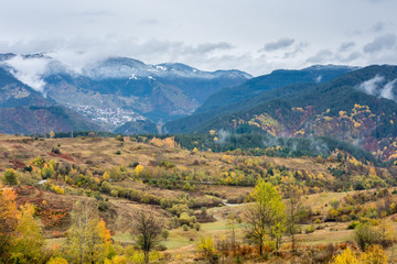Winter in the autumn landscape. Bulgarian Rodopi mountain colored by fall and winter. A village tucked away among hills