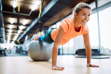Young attractive woman doing push ups using ball - obrazy, fototapety, plakaty