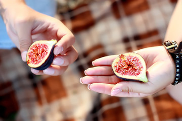  man and woman  hold in their hands a fig on a picnic, close-up