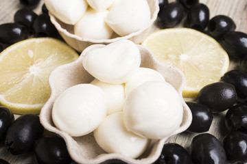 Cheese mozzarella close-up against the background of lemon slices and black olives