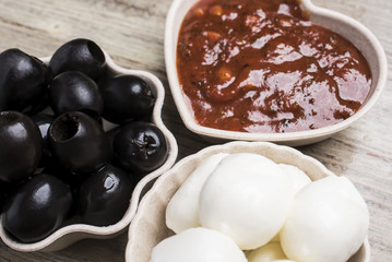 Ingredients for pizza, black olives, mozzarella cheese and tomato sauce