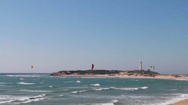 People doing kitesurfing on the beach of Los Canos de Meca, next to the lighthouse of Trafalgar, on the coasts of Cadiz, Spain