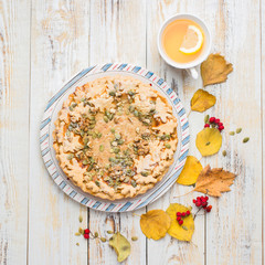Autumn background with pumpkin pie, hot tea, yellowed leaves, book and rug. Perfect sunny autumn. A wooden light white autumn background for you. Copy Space. Place for text. Flat lay, top view