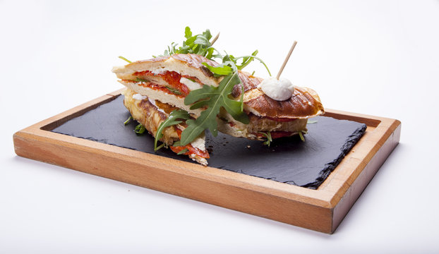 Sandwich with ham,tomato, cucumber and arugula on the wooden cutting board,isolated