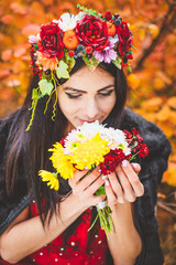 Woman in autumn wreath against a background of red foliage