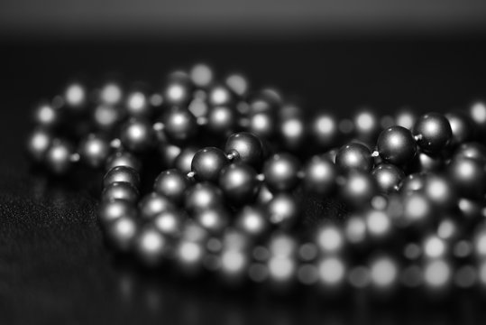 Long beaded necklace on a dark background. Black and white