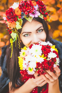 Woman in autumn wreath against a background of red foliage