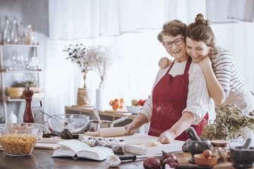 Photo sur Plexiglas Cuisinier Petite-fille étreignant la grand-mère dans la cuisine