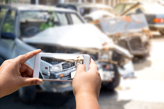 woman is photographing an accident car using a camera from a mobile phone.