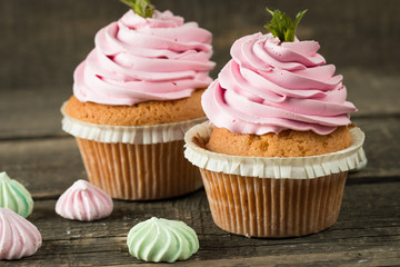 Closeup of cupcakes with vanilla, berries, pink and white cream, chocolate and sprinkles on wooden background. Selective focus. Sweet dessert tasty food concept muffin