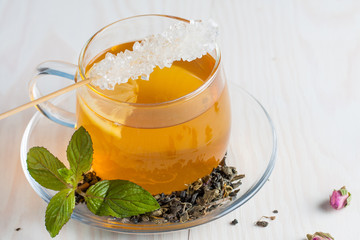 A glass cup of green natural tea with ginger, lemon, mint and honey on wooden rustic background. Healthy drink.