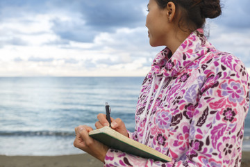 A girl is writing on a beach. Copywriter. Author. Literature. Creativity. Freelancer