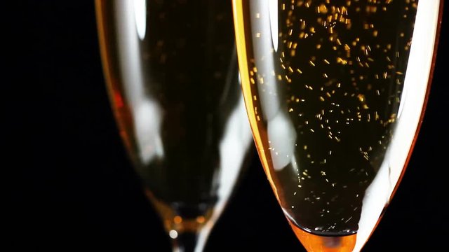Champagne close up in glass with bubbles on black background.