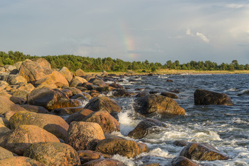 Boulders, forest, shore, evening light, sunset, clouds, blue sky and rainbow on the Baltic Sea. Mohni, small island in Estonia, Europe.