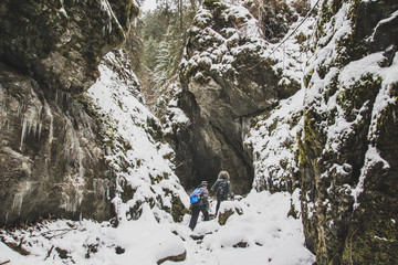 Fototapeta na wymiar A guy and a girl are walking along a snow-covered mountain gorge