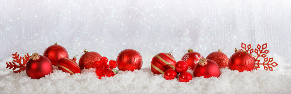 Red Christmas ornaments row on Christmas snowy bokeh background