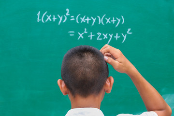 Students stand in front of green chalk board at the classroom. He doubts the mathematical equation...