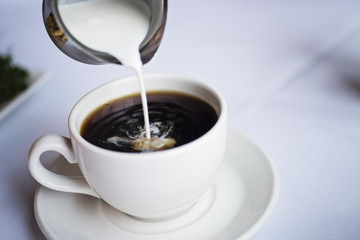 Pouring creamer into a cup of coffee