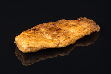 Fried breaded chicken white meat breasts in eggs above black background table with reflections