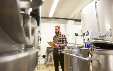 man with clipboard at craft brewery or beer plant