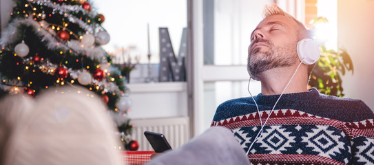 Men listening music at home with feet up at desk