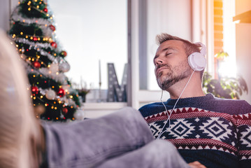Men listening music at home with feet up at desk