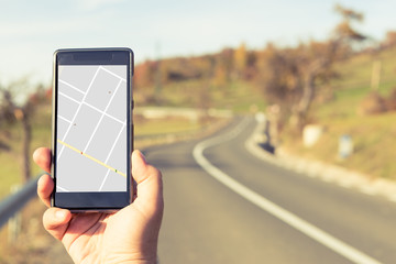 Hand holding smartphone with gps map on autumn outdoor background