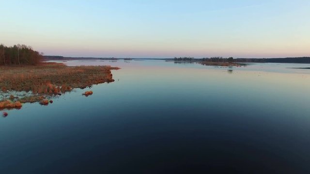4K. Low flight and takeoff over wild lake with ducks in winter on sunset, aerial view.