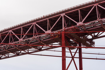 Naklejka premium Detail view of red steel beam suspension bridge in overcast