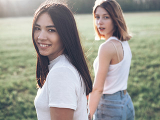 Two girls turned and look at the camera. Outdoors