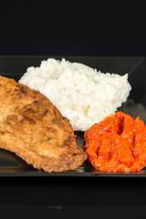 Fried chicken white meat with mashed potatoes and paprika ajvar on the black plate