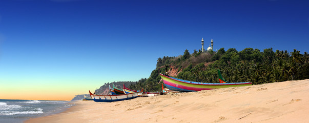 panoramic view of colorful fishermen boats in front of Varkala South Cliff with mosque on top, Kerala, India
