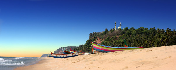 panoramic view of colorful fishermen boats in front of Varkala South Cliff with mosque on top,...