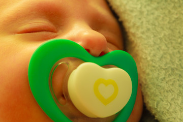 Closeup of little newborn sleeping with teat in mouth