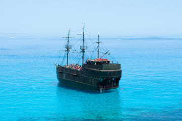 Black pirate ship on the blue sea. Back view