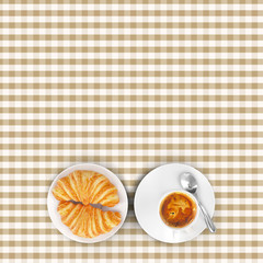 Brown squared tablecloth with cappuccino and croissant