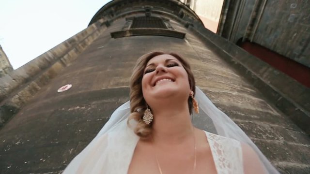 Llook from below at smiling bride while groom jumps over her