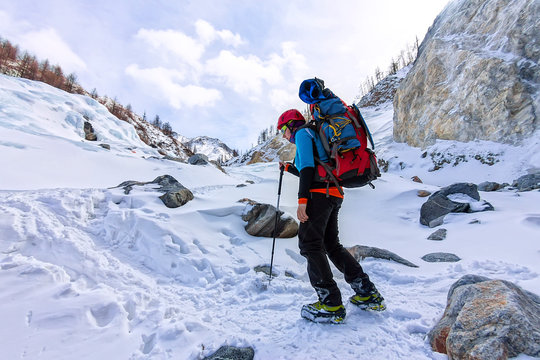 Female mountaineer with backpack, helmet and harness with climbing in mountain
