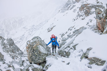 Vrouwelijke bergbeklimmer met rugzak, helm en harnas met klimmen in de bergen