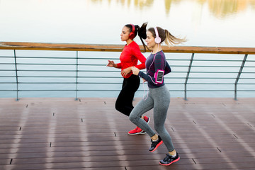 Two young women running by river